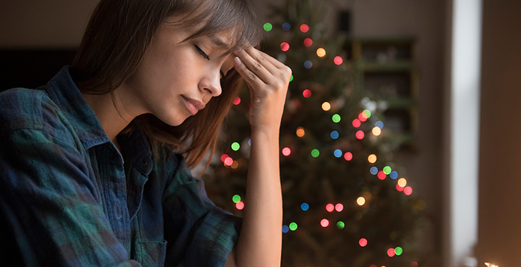Woman looking sad in front of holiday decorations
